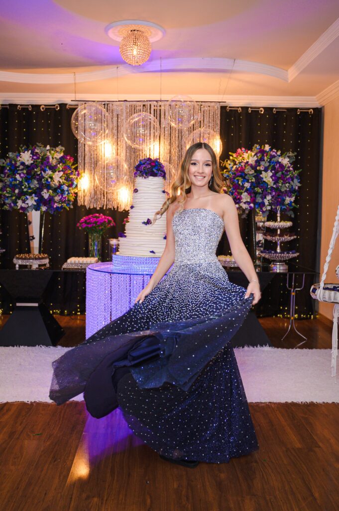 A glamorous woman in a sparkling evening gown poses at a luxurious indoor party setup.