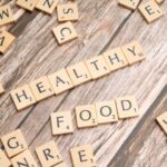 Wooden tiles spelling 'healthy food' on a wooden background creating a natural and organic theme.