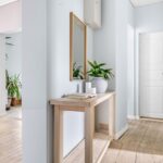 Bright hallway interior featuring minimalist decor, a mirror, and lush plants for a serene ambiance.