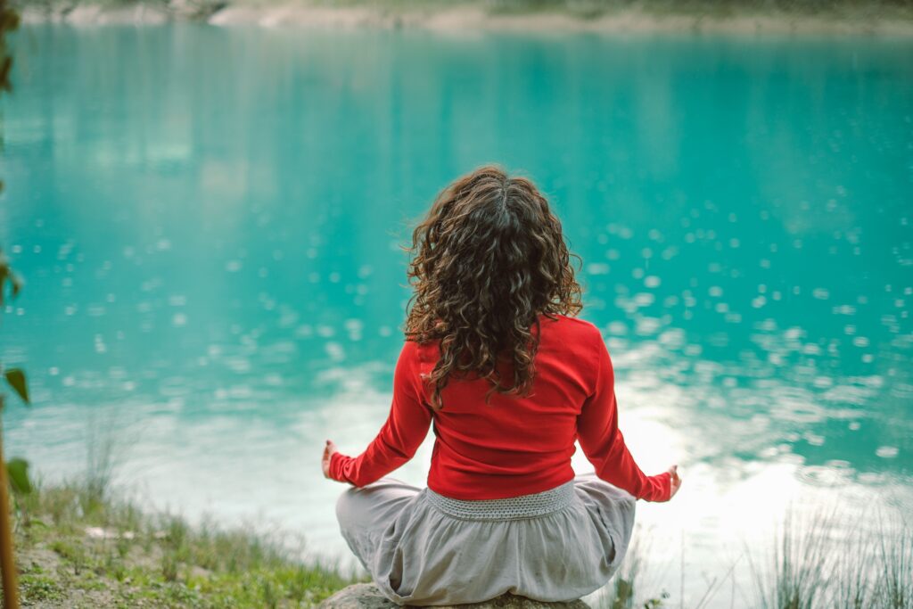 Person meditating calmly beside water