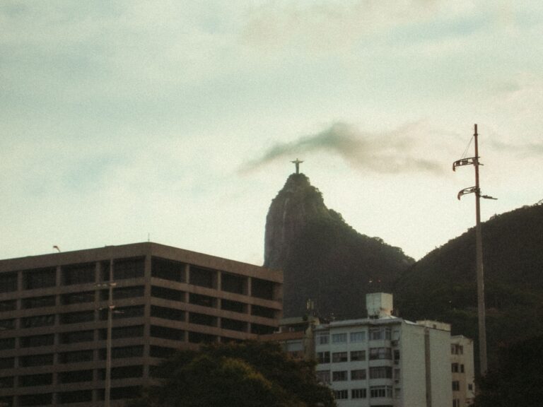 Christ the Redeemer statue on Corcovado Mountain with Rio de Janeiro cityscape under a cloudy sky.