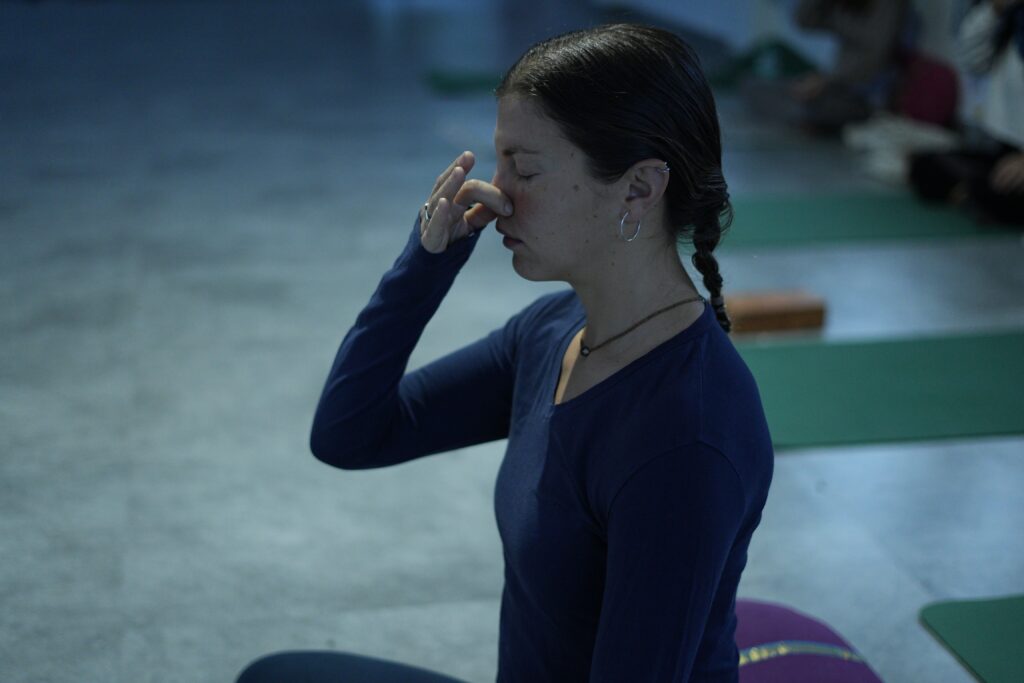 A woman practicing pranayama in a yoga class, focusing on breathing techniques indoors.