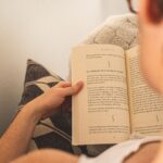 Woman enjoying relaxation by reading a book on a cozy couch indoors.
