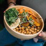 Healthy vegan bowl with chickpeas, kale, carrots, and lemon served fresh.