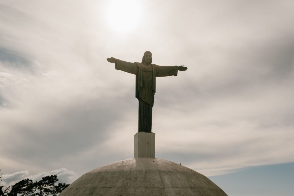 Christ statue stands tall against a dramatic cloudy sky, evoking a sense of peace.
