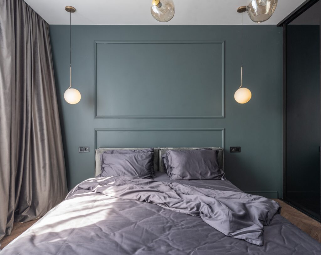 Bedroom accessories in a finished bedroom with grey bedding and pendant lighting