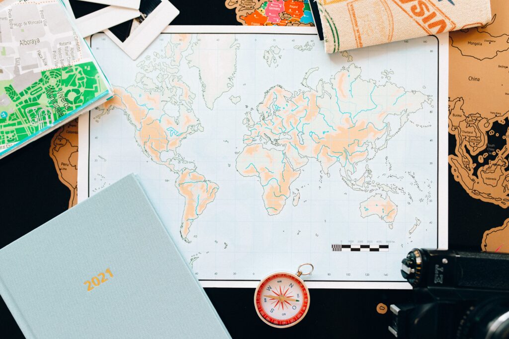 Travel planning flat lay with a world map, compass and planner