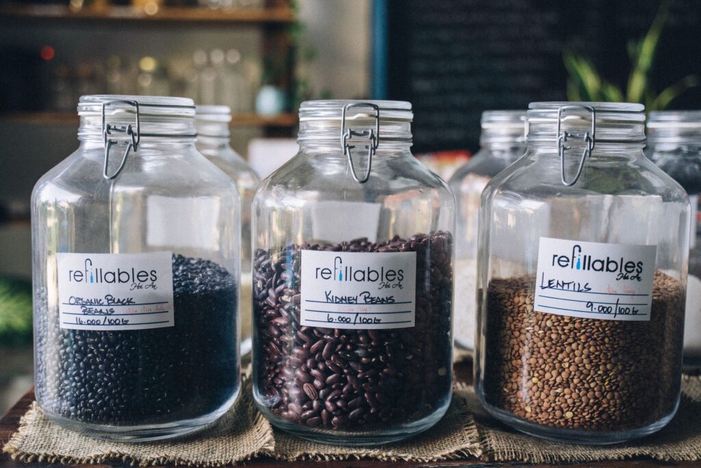 Three refillable glass jars with organic black beans, kidney beans, and lentils in a shop setting.